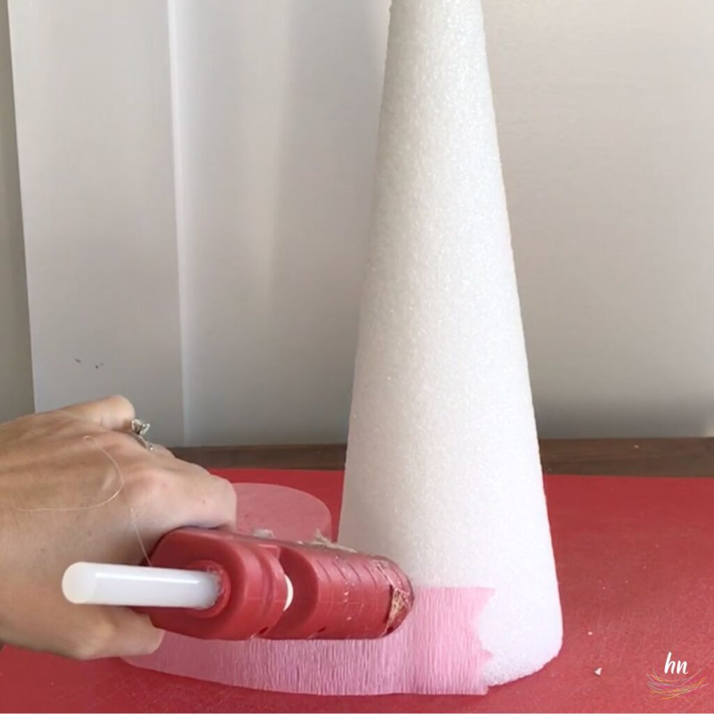 person hot gluing crepe paper to the base of a styrofoam cone