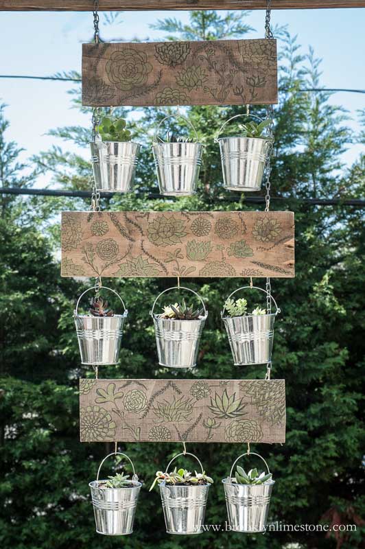 Vertical garden hanging from chain constructed of decorative embellished wood with metal pots