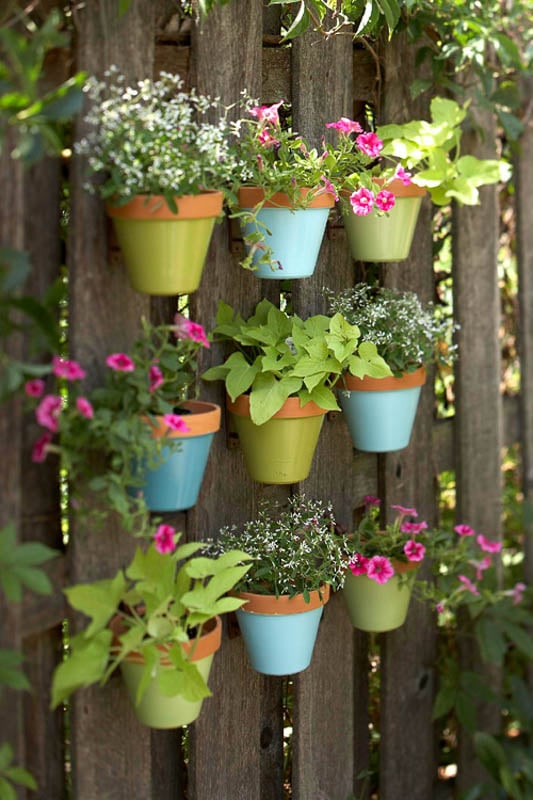 A fun and simple way to garden and add color to an outdoor space. Attach colorfully painted terra cotta pots to a fence.