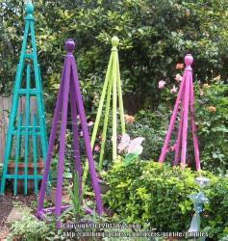 DIY garden pyramids in an outside garden for growing vine plants such as cucumbers and tomatoes.
