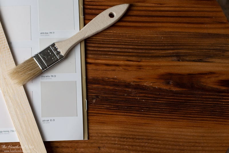 swatch of benjamin moore pale oak on a wood surface with wood paintbrush and paint stirrer