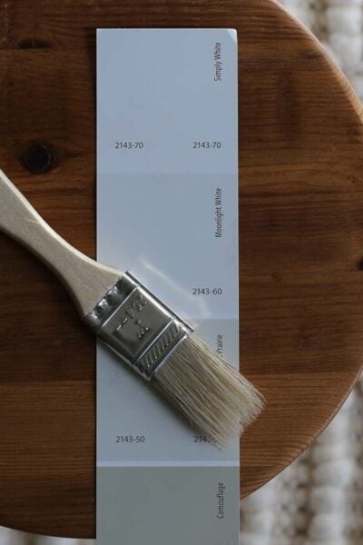 paint chip including Benjamin Moore Simply White on a wood round with paintbrush