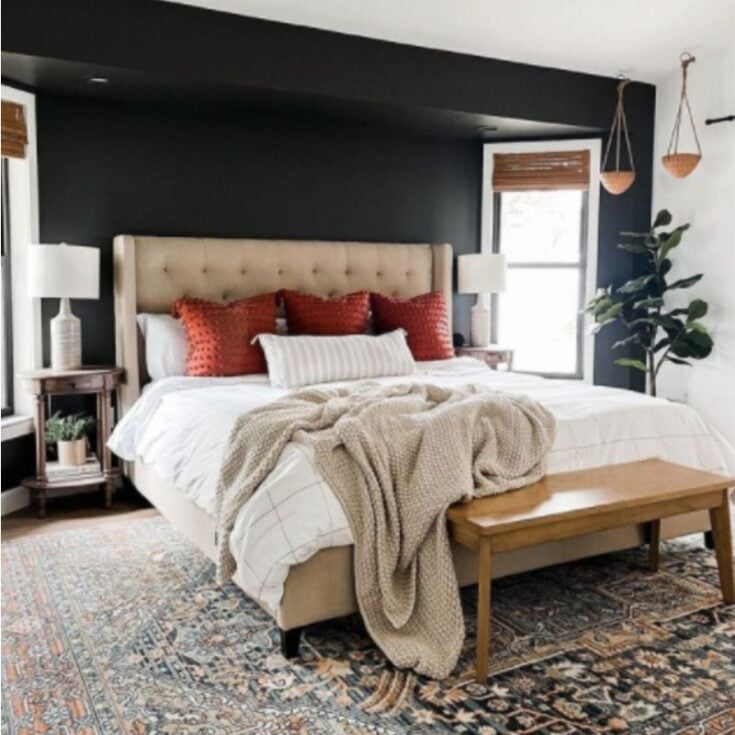 black accent wall behind a bed in a master bedroom with muted oriental rug