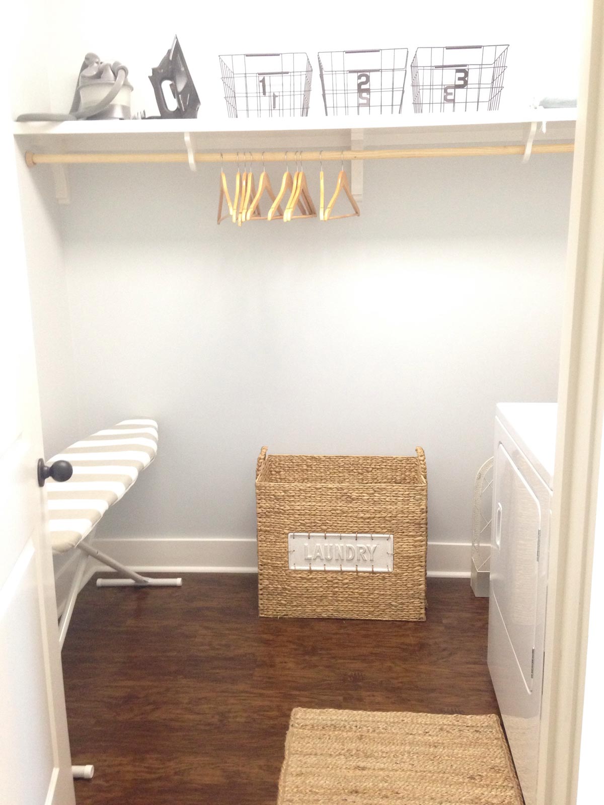 laundry space with single shelf and rod and a wicker basket against a gray wall