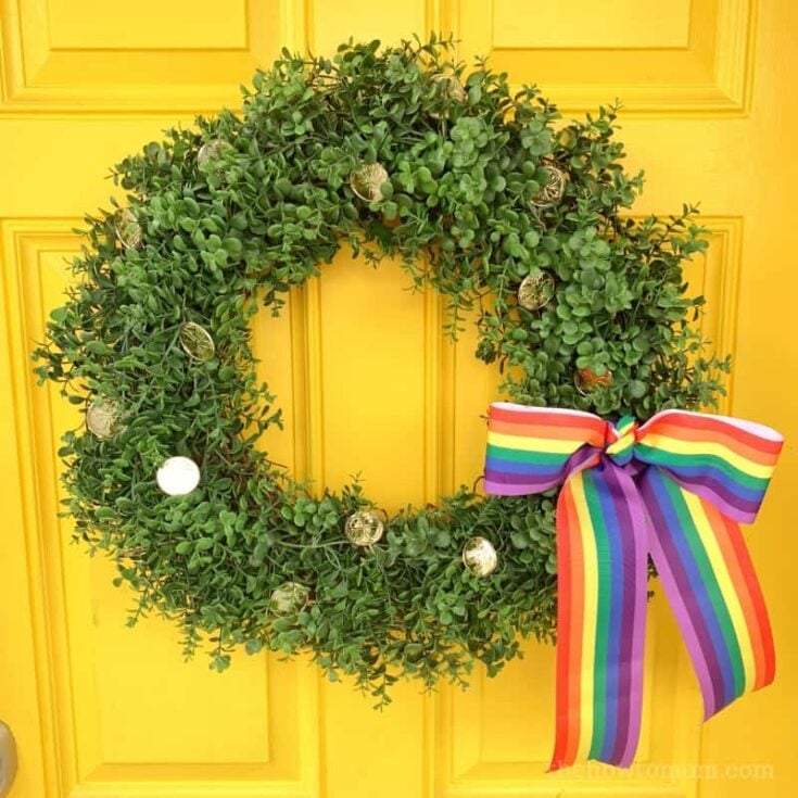 boxwood wreath with gold coins and a rainbow ribbon