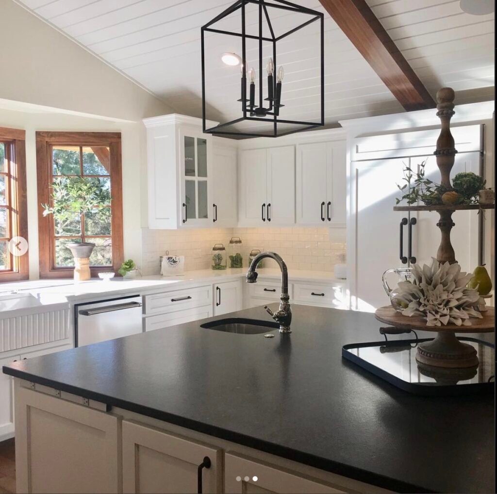 kitchen with black countertops, shiplap vaulted ceiling with wood beams and cabinets painted in SW Creamy
