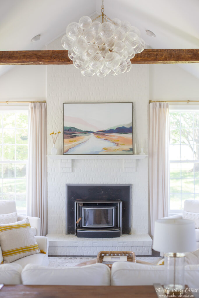 neutral family room makeover with Benjamin Moore Swiss Coffee paint, faux beams, glass bubble chandelier, white sofa with pops of yellow