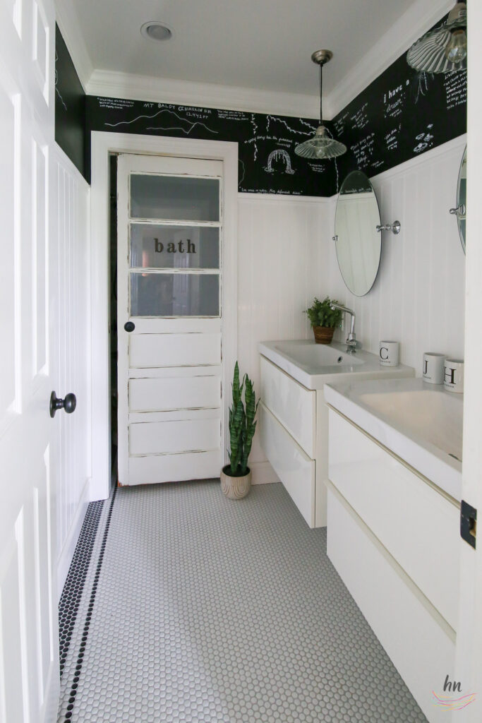 teen bathroom with black and white mosaic tile floor, black ceiling, white subway tile shower enclosure and personalized shower curtain with funny headshots of family pictures, chalkboard paint walls with DIY kids chalk drawings