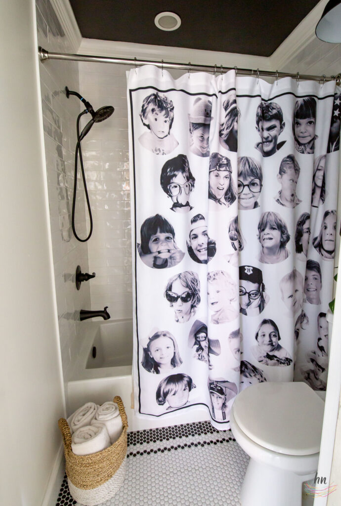 teen bathroom with black and white mosaic tile floor, black ceiling, white subway tile shower enclosure and personalized shower curtain with funny headshots of family pictures