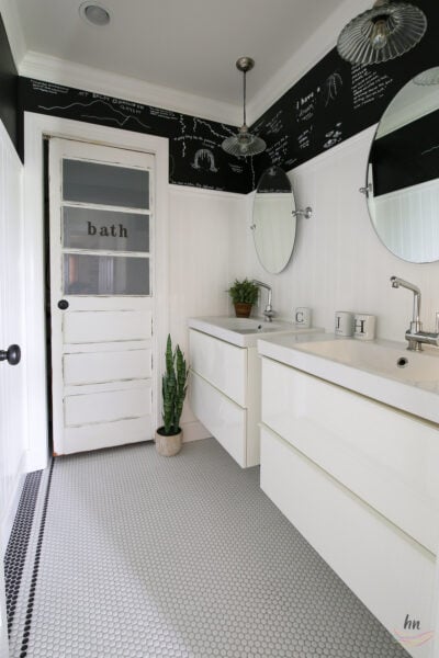 teen bathroom with black and white mosaic tile floor, black ceiling, white subway tile shower enclosure and personalized shower curtain with funny headshots of family pictures, double floating vanities, chalkboard paint walls with DIY kids chalk drawings