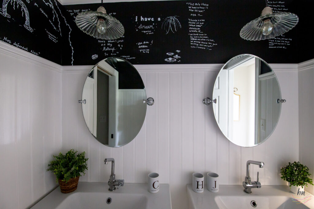 teen bathroom with black and white mosaic tile floor, black ceiling, white subway tile shower enclosure and personalized shower curtain with funny headshots of family pictures, double floating vanities, chalkboard paint walls with DIY kids chalk drawings