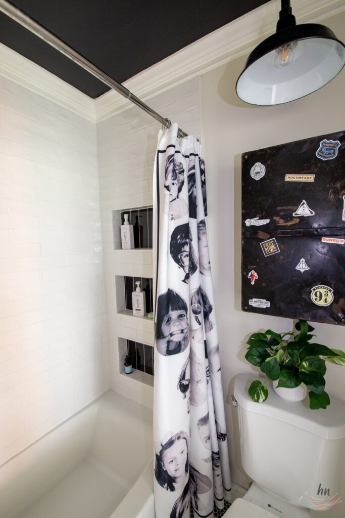 teen bathroom with black and white mosaic tile floor, black ceiling, white subway tile shower enclosure and personalized shower curtain with funny headshots of family pictures, double floating vanities, chalkboard paint walls with DIY kids chalk drawings