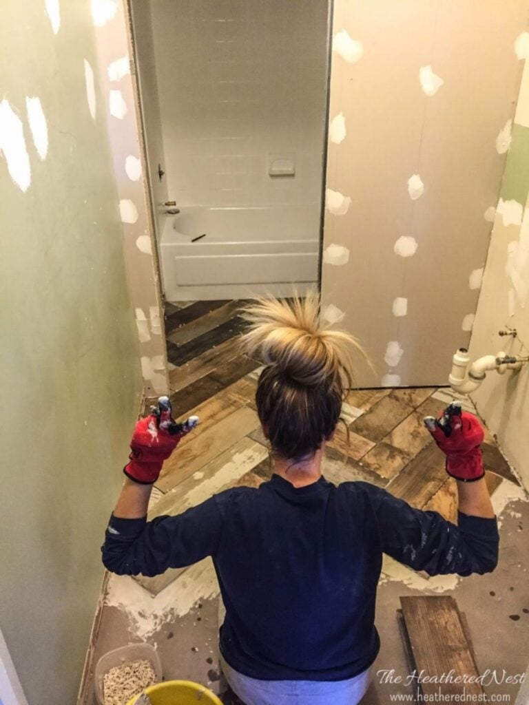 woman kneeling on a bathroom floor while tiling